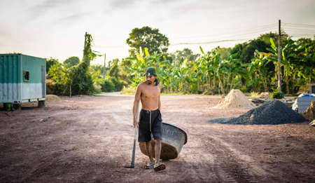 Prachinburi,Thailand - December 30, 2018 : Worker holding hoe and basin in construction siteのeditorial素材