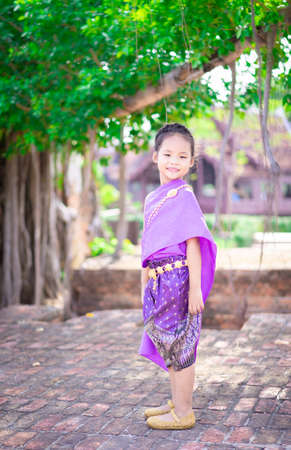 little asian girl shooting wooden slingshot against green tree background, active leisure for kids.の写真素材