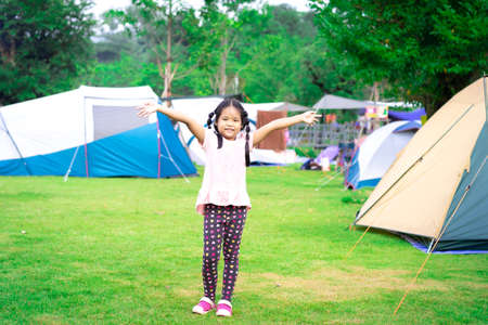 little asian girl shooting wooden slingshot against green tree background, active leisure for kids.の写真素材