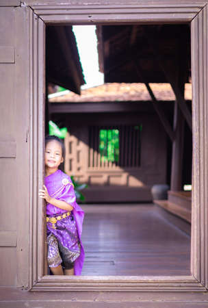 little asian girl in Thai period dress standing in ancient houseの写真素材