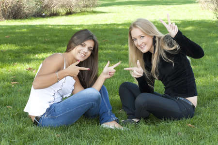 Two girls sitting on the grass in city parkの写真素材