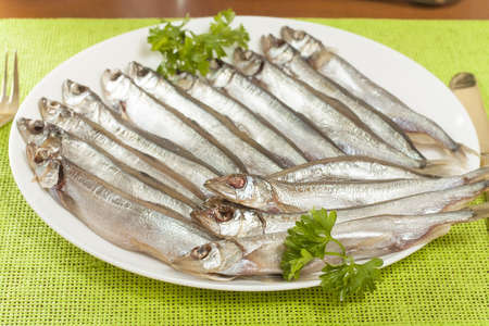 stockfish capelin on a plate closeup with parsleyの写真素材