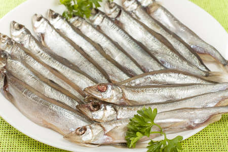 stockfish capelin on a plate closeup with parsleyの写真素材