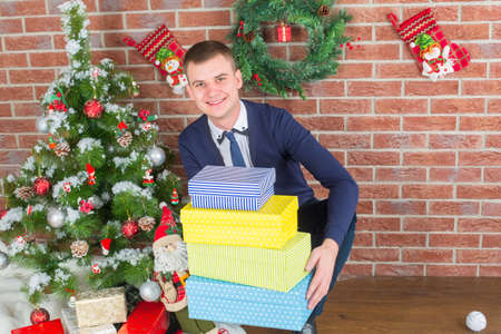 young guy next to a Christmas tree with giftsの写真素材