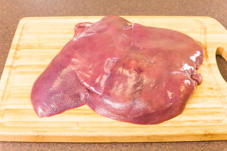 pork raw liver lying on a chopping boardの写真素材