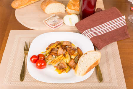 fried potatoes with bacon and pickled tomatoesの写真素材