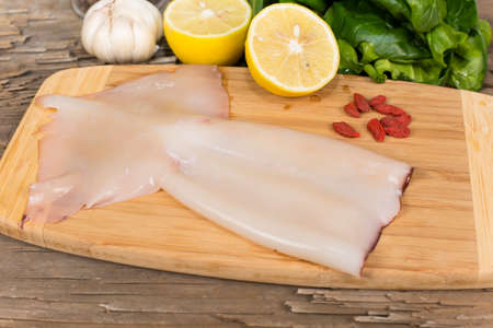 raw squid on a cutting Board on the table from the old boardsの写真素材