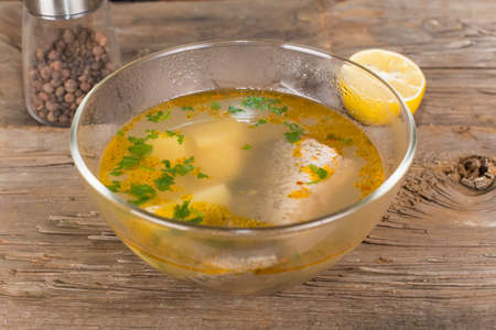 Tsar's fish soup in a glass dish on an old wooden tableの写真素材
