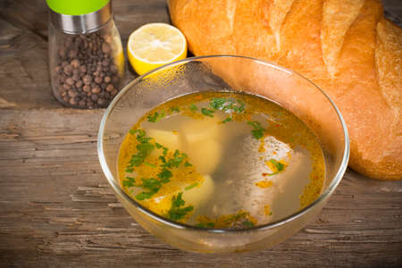 Tsar's fish soup in a glass dish on an old wooden table