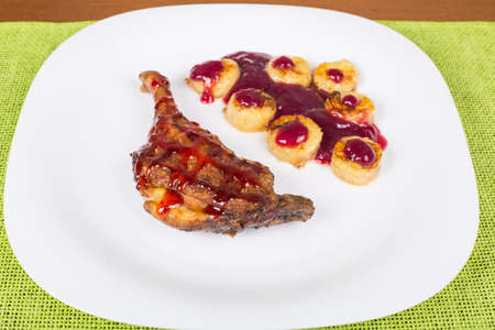 Fried chicken leg with raspberry sauce and fried bananasの写真素材