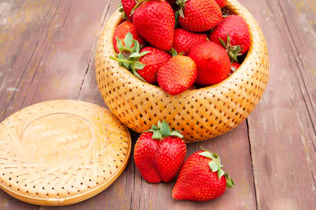 strawberries in a wicker box close-up on an old wooden tableの写真素材