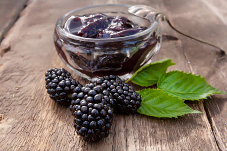 large ripe blackberries and blackberry jam on an old wooden tableの写真素材