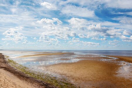 the sandy coastline stretches into the distance, beautiful cloudsの写真素材
