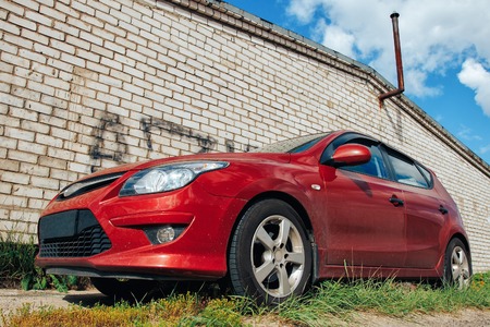 The red car is standing against a brick wallの写真素材