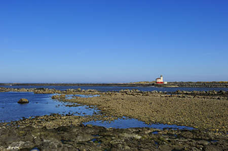 Rocky shorline with lighthouse in the backgroundの写真素材