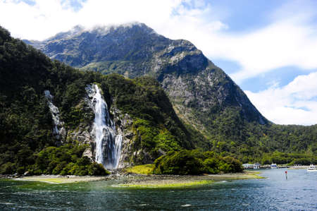 Waterfalls in Milford Sound New Zealand with boats anchoredの写真素材