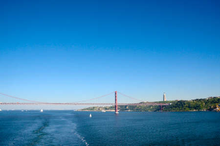 View of April 25th Bridge and Christ the King Statue from the deck of a cruise ship leaving Lisbon...