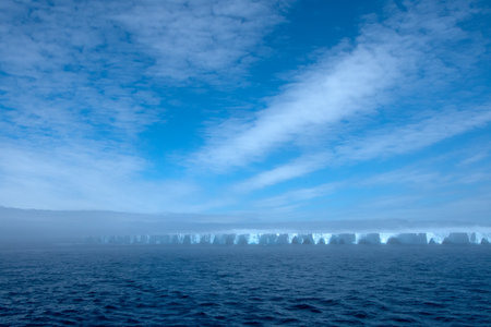 Large blue iceberg surrounded by fog floating in Antarctica.の写真素材