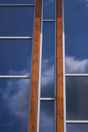 Facade with glass and tropical hardwood reflecting vibrant blue sky with cloudsの写真素材