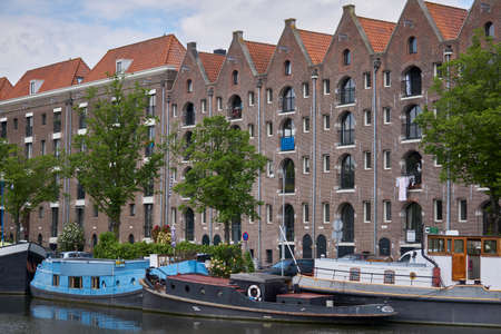 Warehouses with slanted roof in Amsterdam with canal and boatsの写真素材
