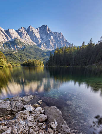 Portrait panorama of the crystal clear water of the Eibsee with the Zugspitze mountain including reflection in the backgroundの写真素材