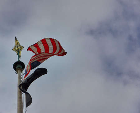 American flag on pole waving in the wind with clouded sky in the backgroundの写真素材