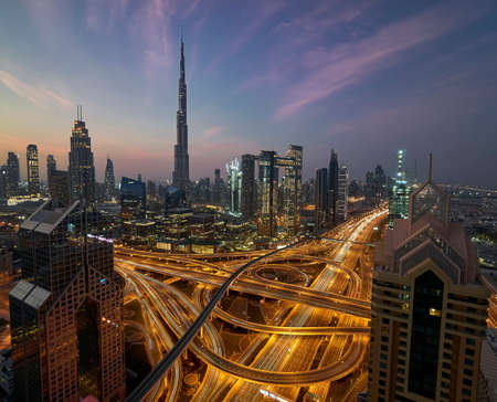 View on highway node and downtown Dubai with tall modernistic skyscrapers during spectacular blue hour with pink and orange cloudsの写真素材