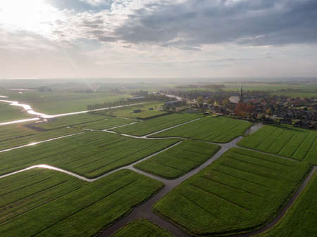 Aerial view of dutch green meadow land with water canals and small villageの写真素材
