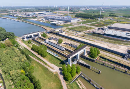 Aerial view of the Princess Beatrix sluice complex in the Netherlands with sustainable energy generating wind mills and solar panels in the background. Waterways transportation infrastructureの写真素材