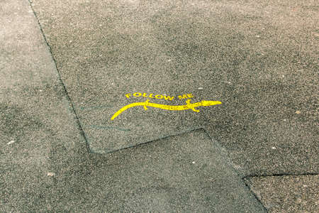 Follow Me pointer painted on asphalt as a yellow salamander.の写真素材