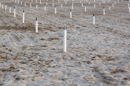 Supporters for beach umbrellas in the end of season on empty sand.の写真素材