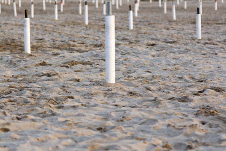 Supporters for beach umbrellas in the end of season on empty sand.の写真素材
