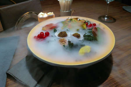 Two truffels candy on a plate, decorated with autumn leaves, berries, cones and smoke, haute cuisineの写真素材