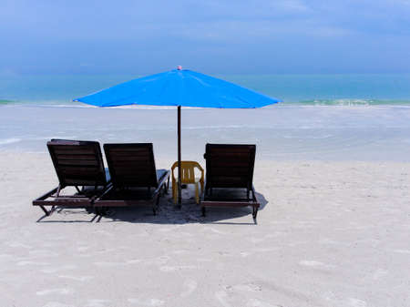 Three sunbeds and a blue umbrella on the beach with white sand on the beach, copy spaceの写真素材