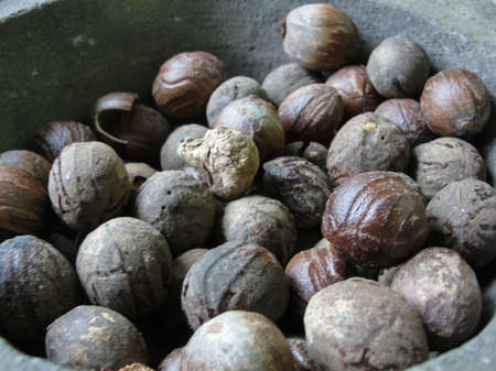 Whole nutmeg in a stone mortar at the market, texture, backgroundの写真素材