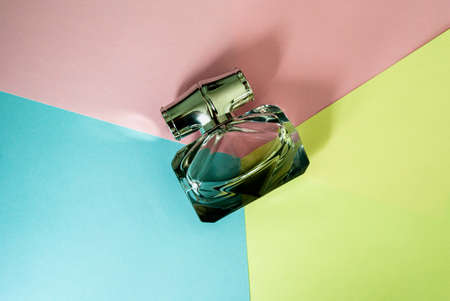 Bottle of perfume on the background of yellow, pink and blue. Top view. Copy spaceの写真素材