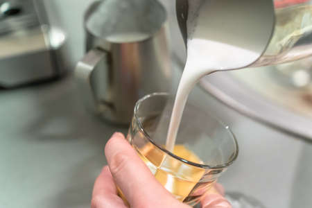 Barista pours milk foam into an espresso glassの写真素材