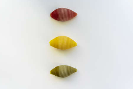 Red, yellow and green conchiglioni on a white background