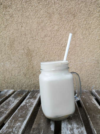 Glass of cold coffee on a background of a wall on a wooden table, front viewの写真素材