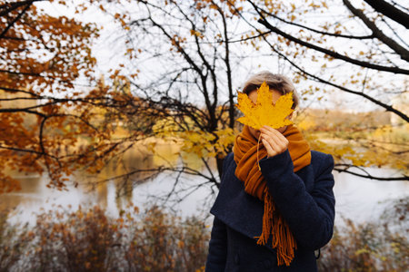 Faceless portrait of a short-haired blonde in the autumn in the parkの写真素材