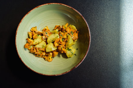 A plate with a vegetarian seasonal lunch. Wild wild mushrooms chanterelles, fried in vegetable oil...