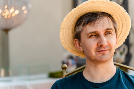 Close-up portrait of a smiling middle-aged man wearing a straw hat and T-shirt