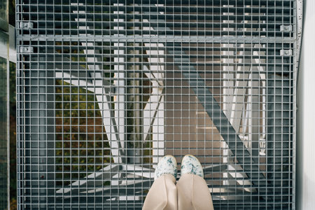 Elevated Perspective: woman feet on suspended mesh metalic bridgeの写真素材