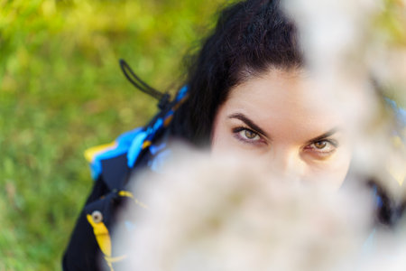 Eyes of attractive young woman through cherry blossom branch in spring in park