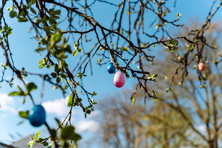 Tree branches in spring with colorful Easter eggs hanging on them
