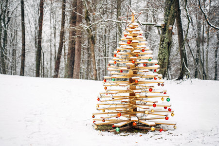 beautiful handmade wooden Christmas tree decorated with festive balls in a snowy forest.の写真素材