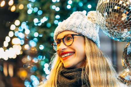 young woman in winter hat in front of festive lights.の写真素材