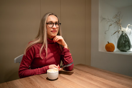 young woman in glasses with cappuccino in cafe.の写真素材