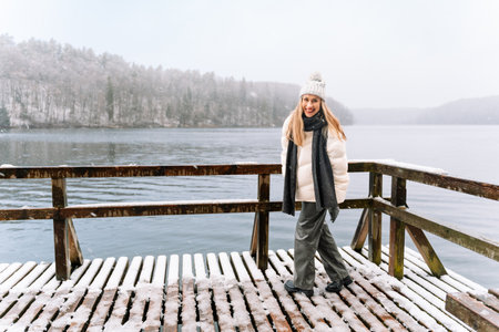 cheerful woman enjoying winter by a lake on a snowy dayの写真素材