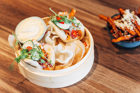 Asian Bao Buns with Fresh Herbs and Crunchy Toppings in a Bamboo Steamer with Sauceの写真素材